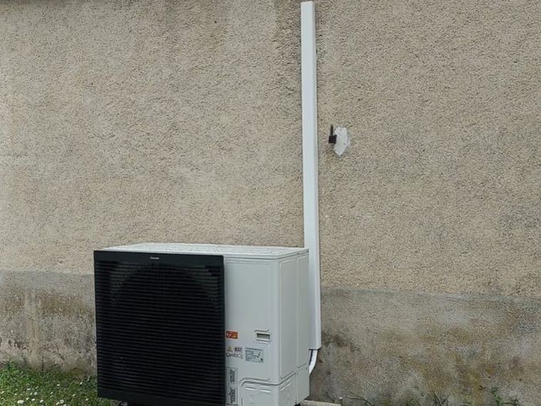 Pompe à chaleur air-eau installée contre la façade d’une maison ancienne